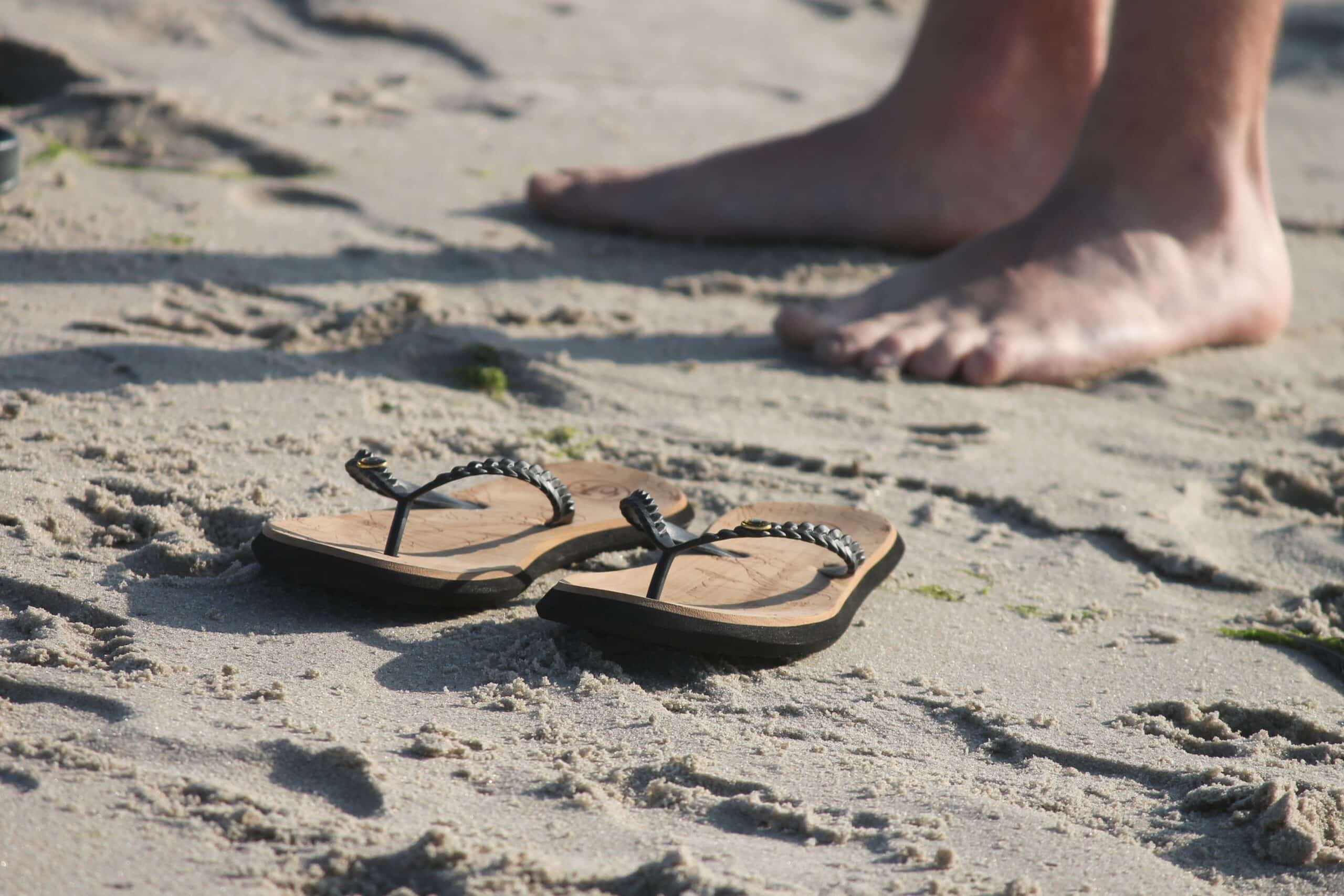 Пасть к ногам. Шлепки на песке. Тапочки для пляжа. Песок в сандалях. Сандалии для пляжа.